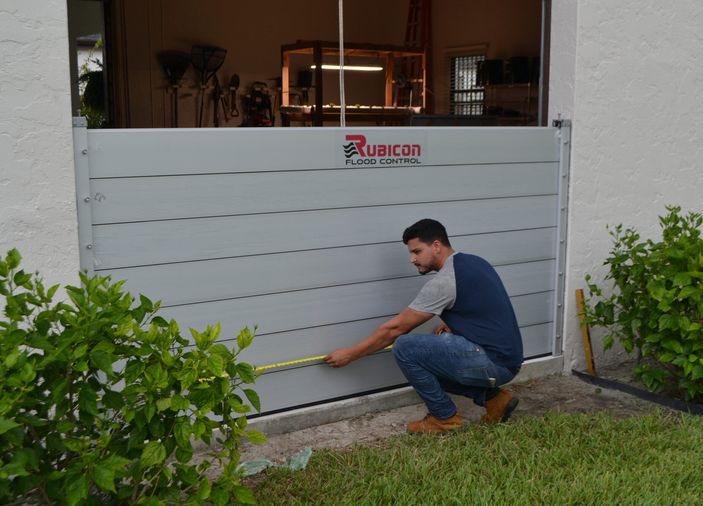 Rubicon technician measuring a BarrierX garage flood barrier installation